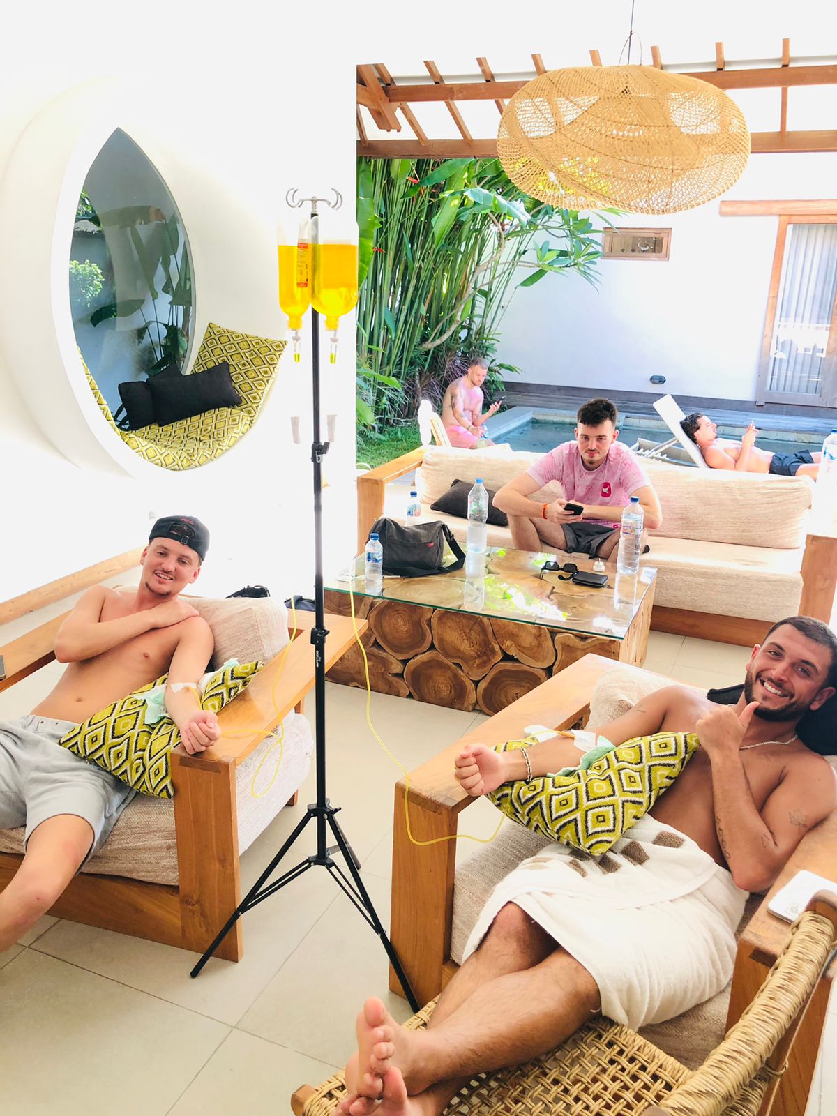 Two men receiving mobile IV drip therapy while relaxing in a luxury Bali villa lounge.